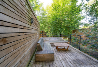 Udendørs træterrasse med bænk og bord ved The Cottage by YourNature, omgivet af skov i Belgien.