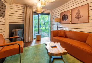 Moderne woonkamer in The Cottage by YourNature in België met oranje meubels en uitzicht op het bos.
