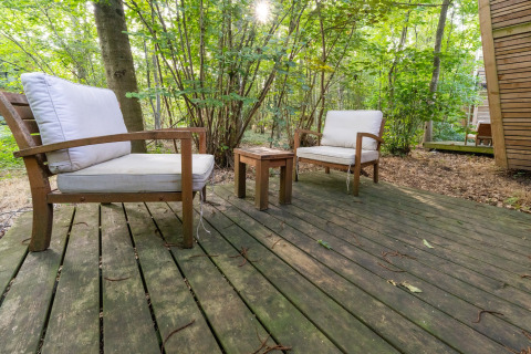 Houten terras met twee comfortabele stoelen en tafeltje, omgeven door bos bij The Cottage by YourNature in België.
