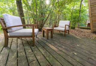 Houten terras met twee comfortabele stoelen en tafeltje, omgeven door bos bij The Cottage by YourNature in België.