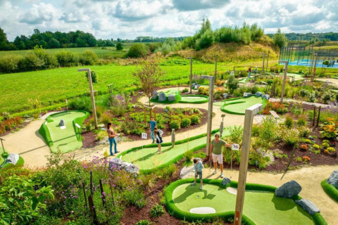 Familier spiller minigolf i grønne omgivelser ved The Lodge by YourNature i Belgien under en skyet himmel.