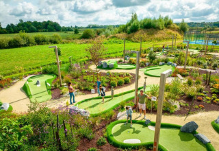 Familier spiller minigolf i grønne omgivelser ved The Lodge by YourNature i Belgien under en skyet himmel.