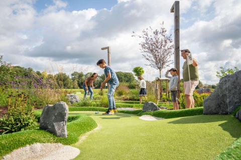 Familie spielt gemeinsam Minigolf auf einer gepflegten Outdoor-Anlage bei einem Glamping-Resort.