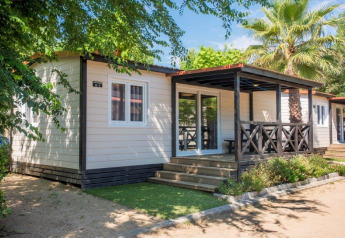 Modern mobiel huisje op Camping Solmar - XALET CONFORT met houten terras en palmbomen in de tuin.