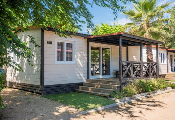 Casa mobile moderna al Camping Solmar - XALET CONFORT con veranda in legno e piante tropicali.