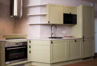 Modern kitchen at The Easy Accessible Leaf by YourNature lodge with green cabinets, oven, and microwave.