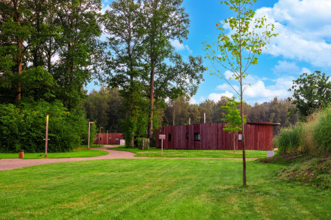 Die Easy Accessible Leaf Lodge von YourNature steht inmitten grüner Wiesen und dichter Bäume.