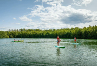 Gäste paddeln und stehen auf Paddleboards auf einem See bei The Easy Accessible Leaf by YourNature in Belgien.
