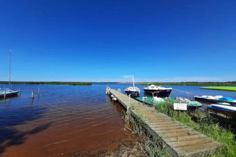 Muelle de madera con barcos en Houseboat «am Gräbendorfer See» bajo cielo azul claro en Alemania.