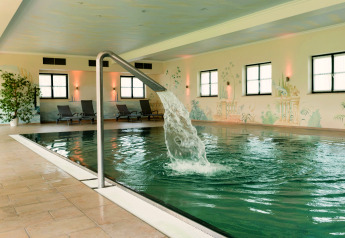 Piscina interna con cascata e lettini presso lo Chalet «Bungalow» in Germania.