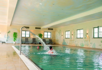 Piscina coperta al Chalet «Bungalow» in Germania con lettini, piante e ospiti che nuotano.
