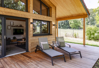 Terrazza in legno coperta allo Chalet «Bungalow» in Germania con due lettini e vista sul verde circostante.