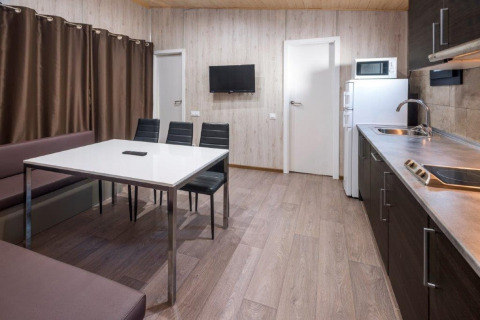 Casa mobile moderna con cucina, tavolo, sedie e TV al Camping Solmar, Spagna.