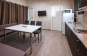 Moderne mobilhomekeuken en eetruimte met tafel, stoelen, tv bij Camping Solmar, Spanje.