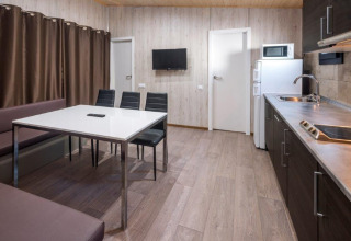 Casa mobile moderna con cucina, tavolo, sedie e TV al Camping Solmar, Spagna.