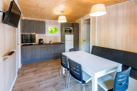 Cucina moderna e zona pranzo nel mobil home Camping Solmar XALET CONFORT in Spagna, interno in legno.