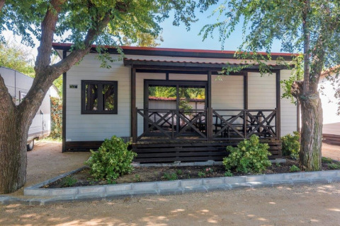 Stacaravan met veranda en tuin bij Camping Solmar XALET CONFORT in Spanje, omgeven door bomen.