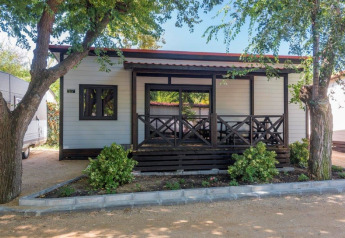 Stacaravan met veranda en tuin bij Camping Solmar XALET CONFORT in Spanje, omgeven door bomen.