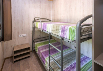 Een kamer in een mobilhome op Camping Solmar in Spanje met stapelbedden en gestreept beddengoed.