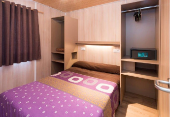 Slaapkamer in een mobilhome met tweepersoonsbed, kast en kluis bij Camping Solmar in Spanje.