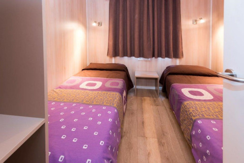 Twee single bedden met paarse dekens in een mobilhome op Camping Solmar - XALET CONFORT in Spanje.