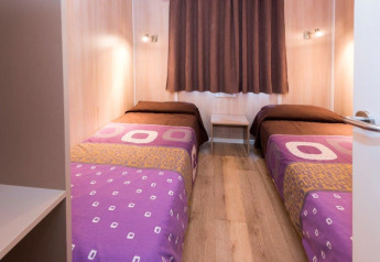 Twee single bedden met paarse dekens in een mobilhome op Camping Solmar - XALET CONFORT in Spanje.