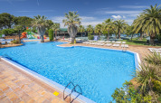 Swimmingpool med palmer og liggestole på Camping Solmar - XALET i Spanien, ideel til afslapning og feriehygge.