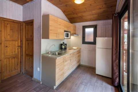 Cuisine moderne de chalet au Camping Solmar - XALET en Espagne, avec plafond en bois, frigo et fenêtre.