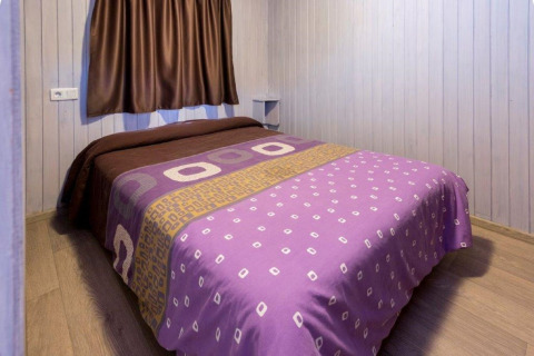 Chambre confortable d'un chalet au Camping Solmar en Espagne, avec couverture violette et murs en bois.
