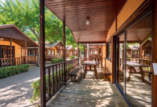 Chalets en bois avec terrasses et bancs au Camping Solmar - XALET en Espagne, ambiance ensoleillée.
