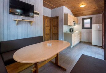 Indvendig udsigt over Camping Solmar - XALET i Spanien med spisebord, køkken og sofa.