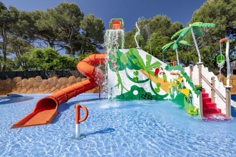 Waterspeelplaats bij mobiel huis met kleurrijke glijbaan, speeltoestellen en tropische decoraties.