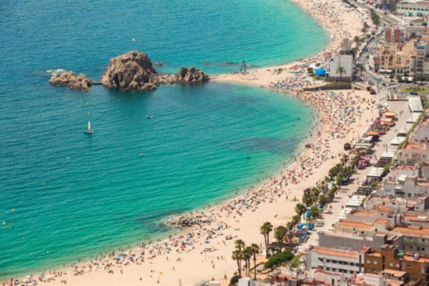 Vue depuis Camping Solmar - XALET en Espagne, plage animée, mer turquoise et rochers impressionnants.