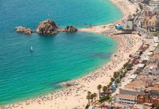 Vue depuis Camping Solmar - XALET en Espagne, plage animée, mer turquoise et rochers impressionnants.