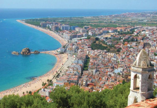 Udsigt over stranden og byen set fra Camping Solmar - XALET i Spanien, med kystlinje og hav i baggrunden.
