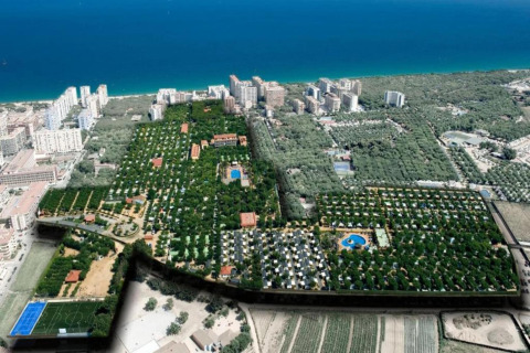 Luchtfoto van een luxueuze glamping vlak bij het strand, met zwembaden, sportvelden en bomen.