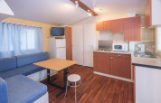 Interno della casa mobile Camping Solmar - COTTAGE B in Spagna con cucina, zona pranzo e divano.