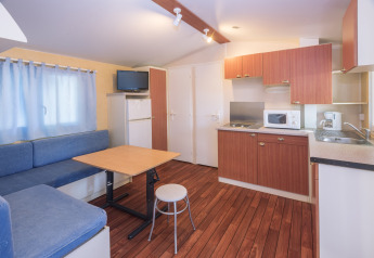 Interno della casa mobile Camping Solmar - COTTAGE B in Spagna con cucina, zona pranzo e divano.