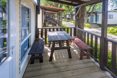 Houten veranda met picknicktafel en banken bij de stacaravans van Camping Solmar - COTTAGE B, Spanje.