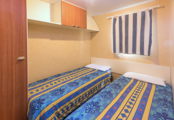 Due letti singoli con copriletti colorati nella camera da letto della casa mobile Camping Solmar - COTTAGE B in Spagna.