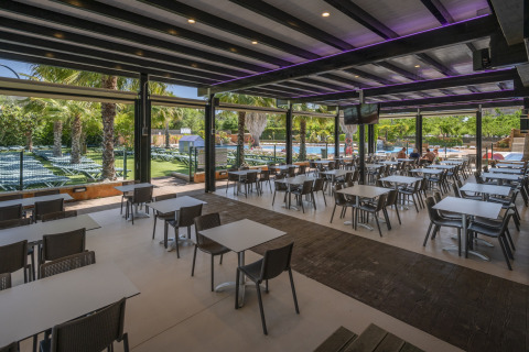 Overdekte eetruimte bij Camping Solmar - COTTAGE B in Spanje met uitzicht op zwembad en ligbedden.