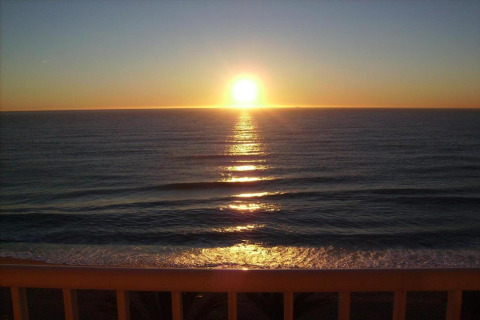 Zonsondergang boven zee vanaf het terras bij Camping Solmar - COTTAGE B, Spanje, met rustige golven.