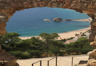 Udsigt over stranden og havet gennem en stenhvælving fra Camping Solmar - COTTAGE B i Spanien.