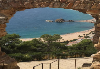 Vista su spiaggia e mare attraverso un arco di pietra da Camping Solmar - COTTAGE B in Spagna.
