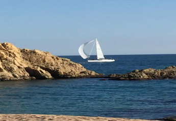 Foto scattata al Camping Solmar - COTTAGE B in Spagna, con scogli, mare blu e una barca a vela bianca.