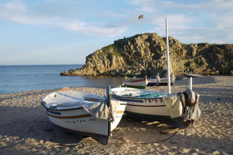 Både på sandstrand med klippeudsigt og hav i baggrunden, taget nær Camping Solmar i Spanien.