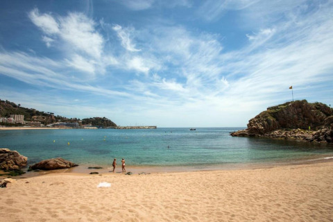 Uitzicht vanaf Camping Solmar - COTTAGE B in Spanje: zandstrand, kalme zee, rotsen en blauwe lucht.