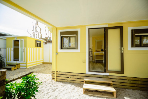 Buitenaanzicht van Miramar Mobile Home CINQUE TERRE in Spanje, gele gevel met treden en veranda.