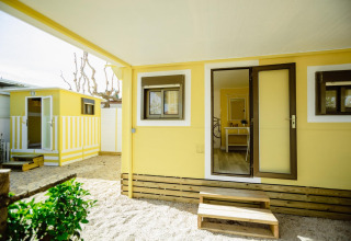 Buitenaanzicht van Miramar Mobile Home CINQUE TERRE in Spanje, gele gevel met treden en veranda.