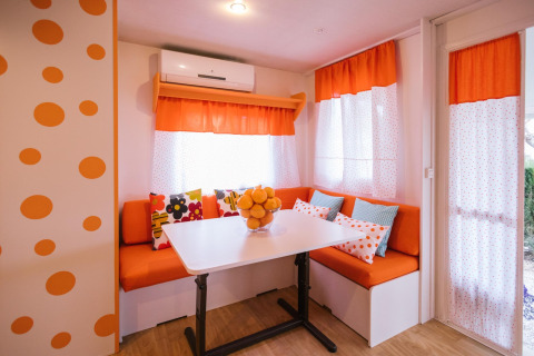 Kleurrijke eethoek in Miramar Mobile home CINQUE TERRE, Spanje, met oranje accenten en stippenpatroon.